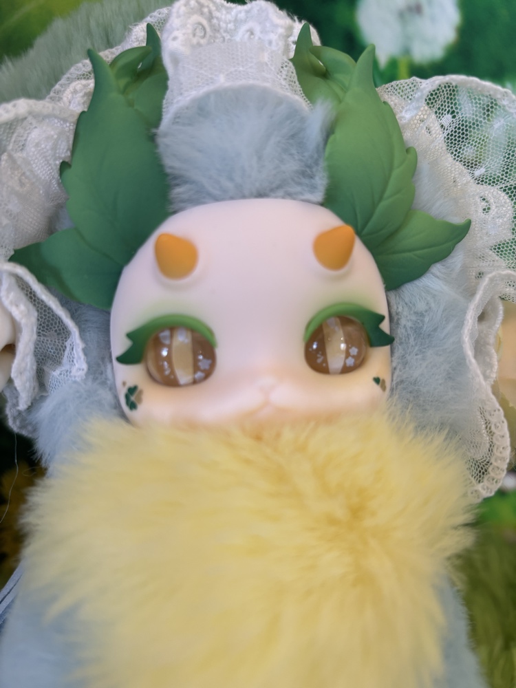 Macro close up of the Tutulong Herbalist plush face plate showing glossy golden star eyes and green mascara.