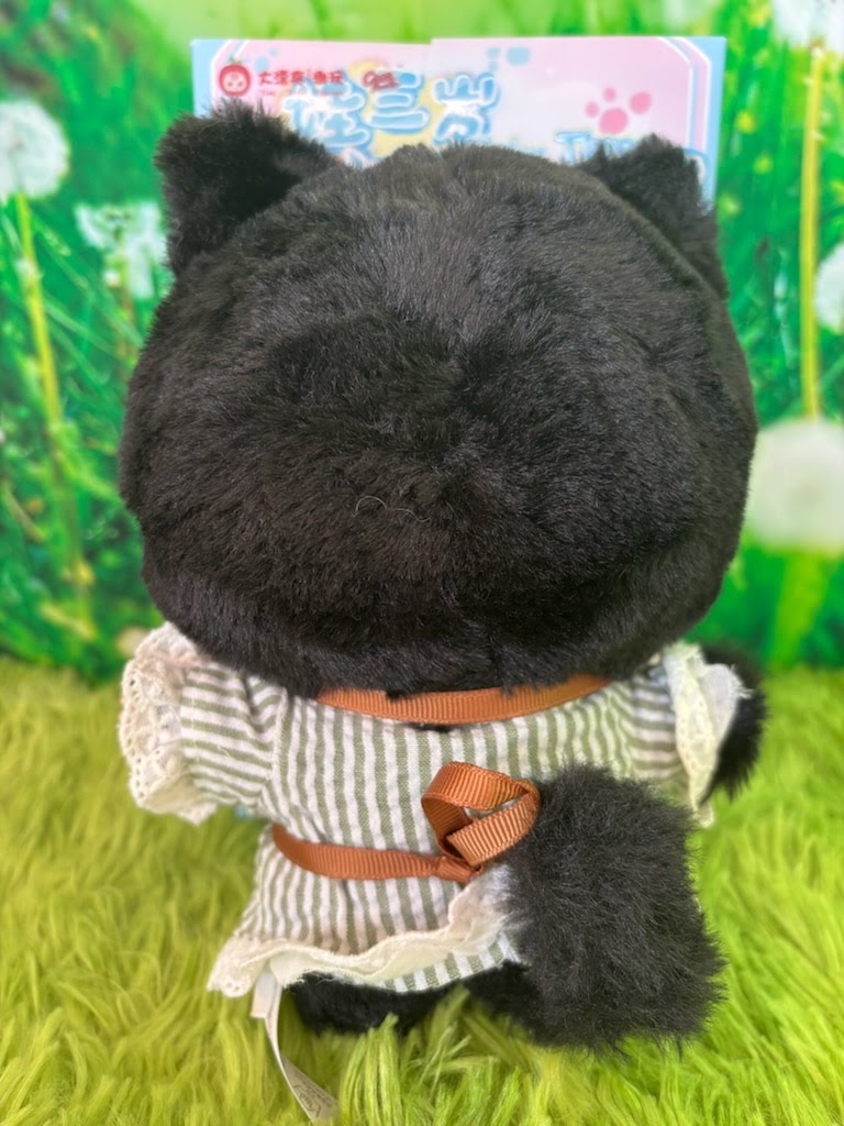 Rear view of Baby Three black cat plush showing its fluffy tail and brown ribbon apron ties.
