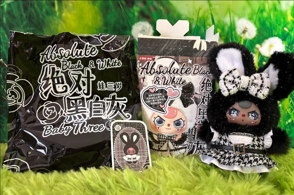 Baby Three Absolute Black and White series Star Twinkle plush standing next to its foil bag, box, and collectible art card