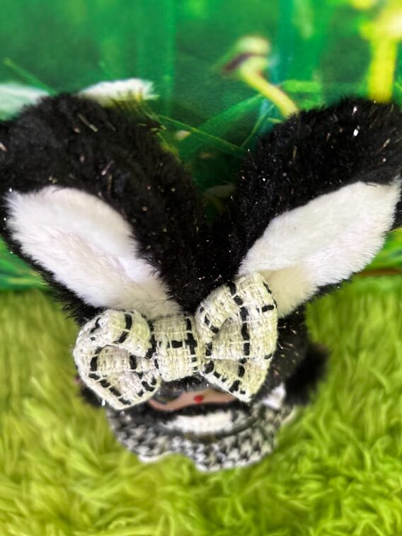 Top-down close-up of Baby Three Star Twinkle plush showing the textured black and white plaid bow secured between her ears